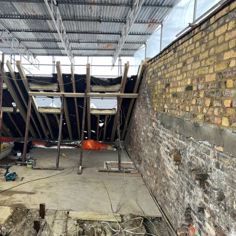 Construction site showing exposed brick wall and scaffolding. building a loft extension raising the parapet wall.